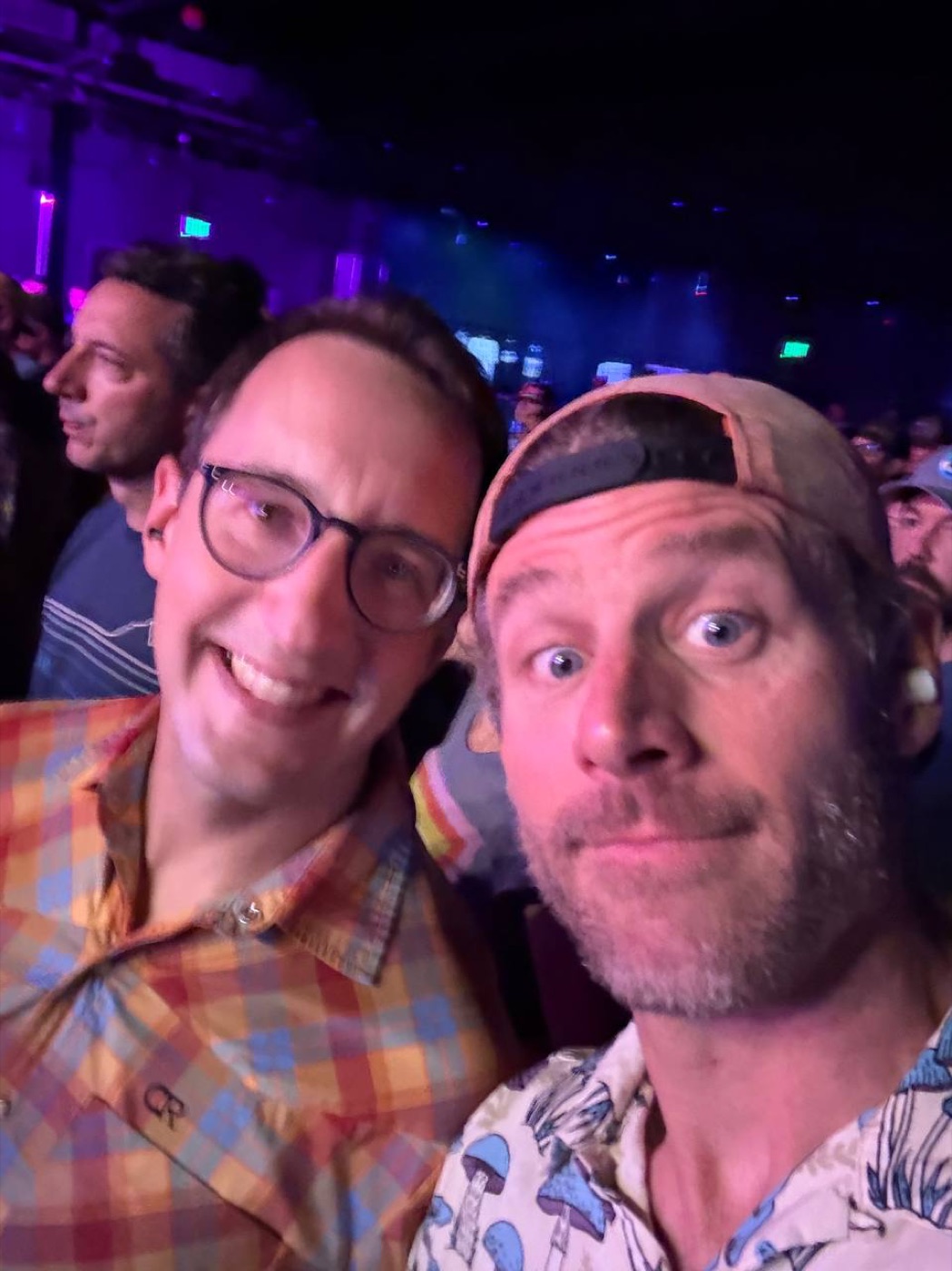 Two friends grinning in a purple-lit concert crowd at Treefort Music Hall.